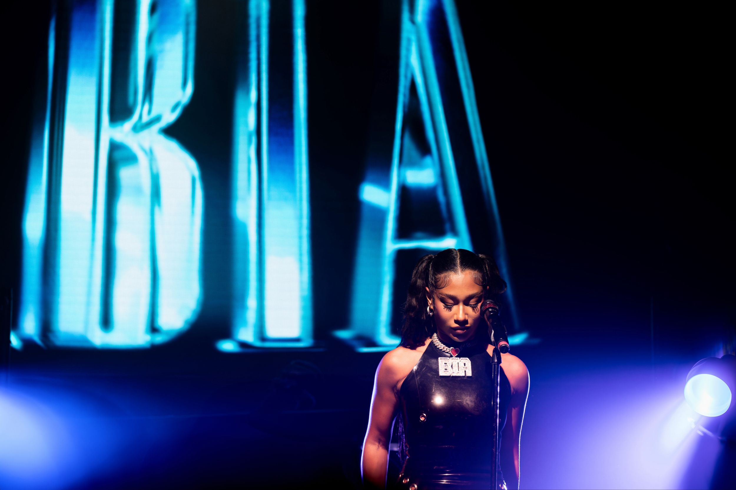 Concert performer silhouetted against blue stage lighting with 'BIA' text display.
