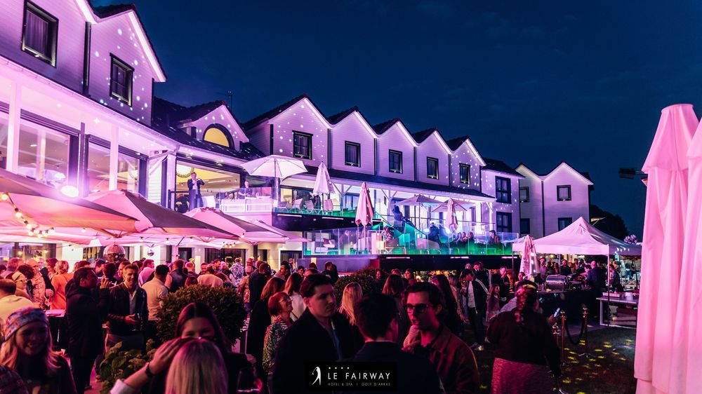 Large outdoor evening crowd at Le Fairway hotel event with colorful lighting and festive atmosphere.