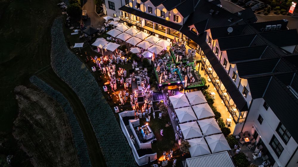 Aerial night view of a crowded outdoor event venue with glowing lights and white tent structures.
