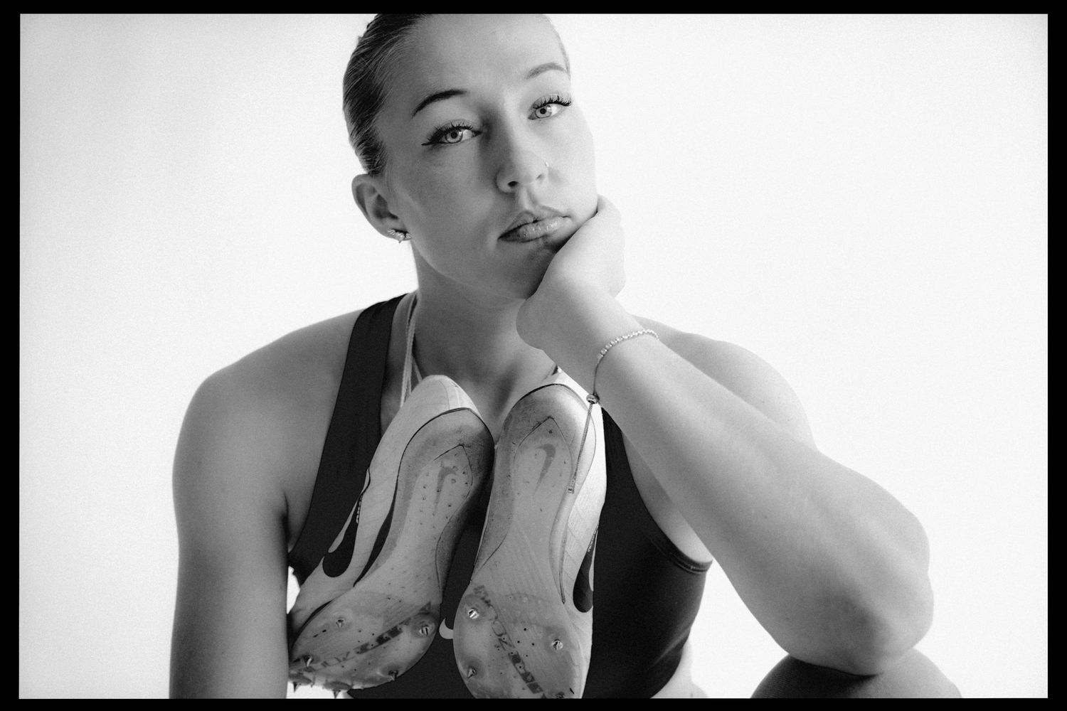 A woman in black and white photography sticks her tongue out playfully while posing for a portrait series.