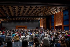 Large conference hall filled with attendees during a presentation.