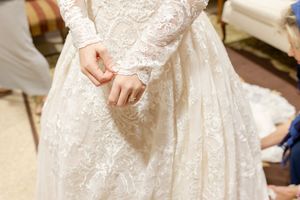Close-up detail of lace wedding dress with long sleeves.