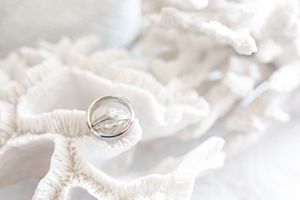 Close-up of wedding rings resting on white lace fabric with soft lighting.
