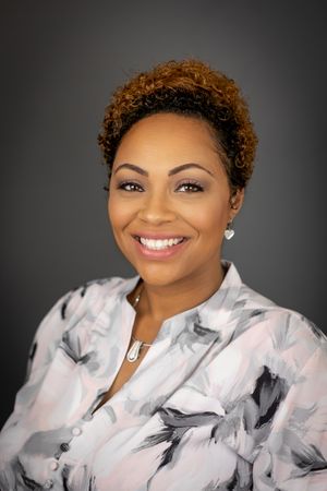 Professional studio portrait against a dark grey background.