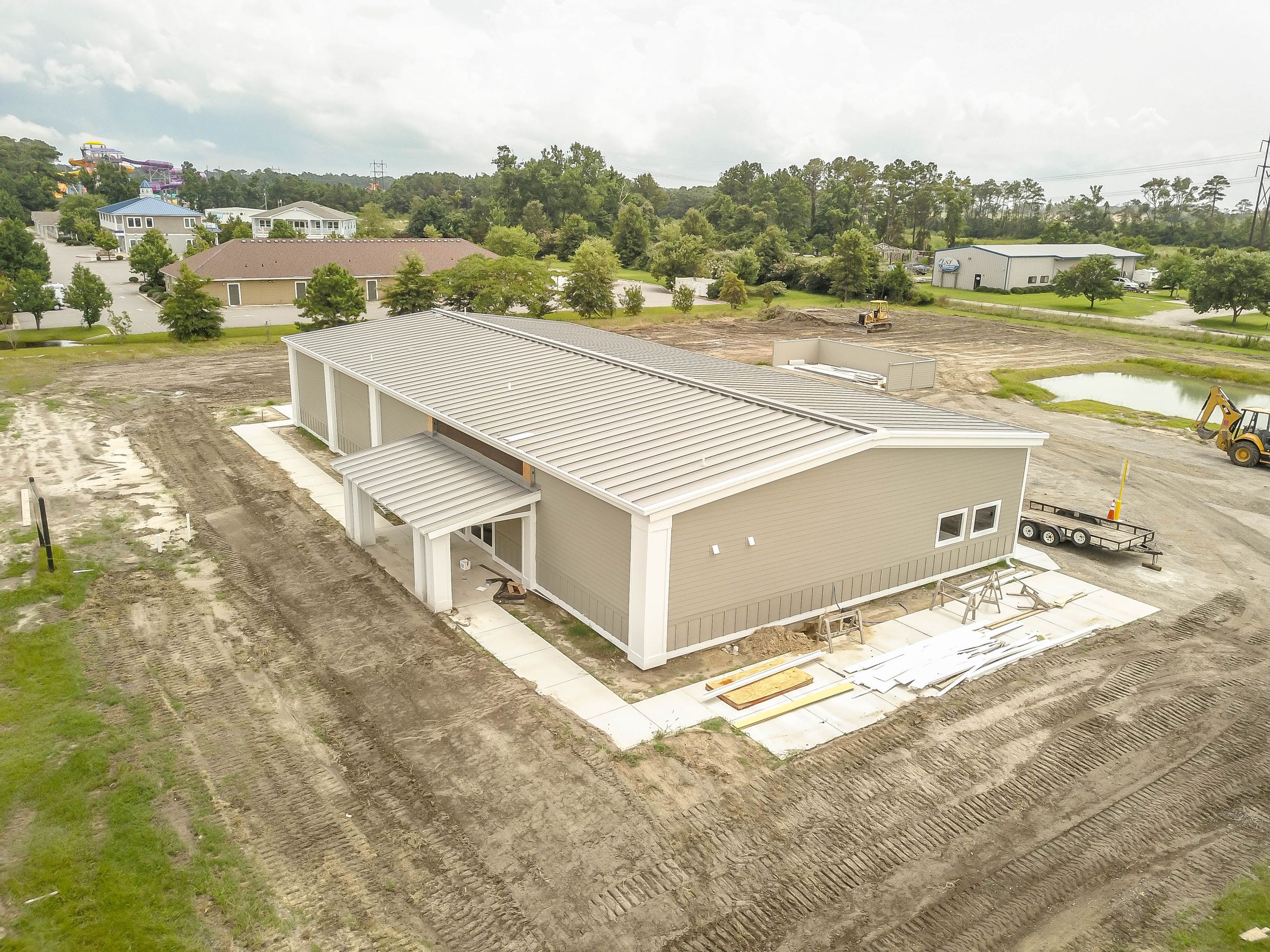 Aerial drone view of a large commercial building under construction with surrounding residential areas.