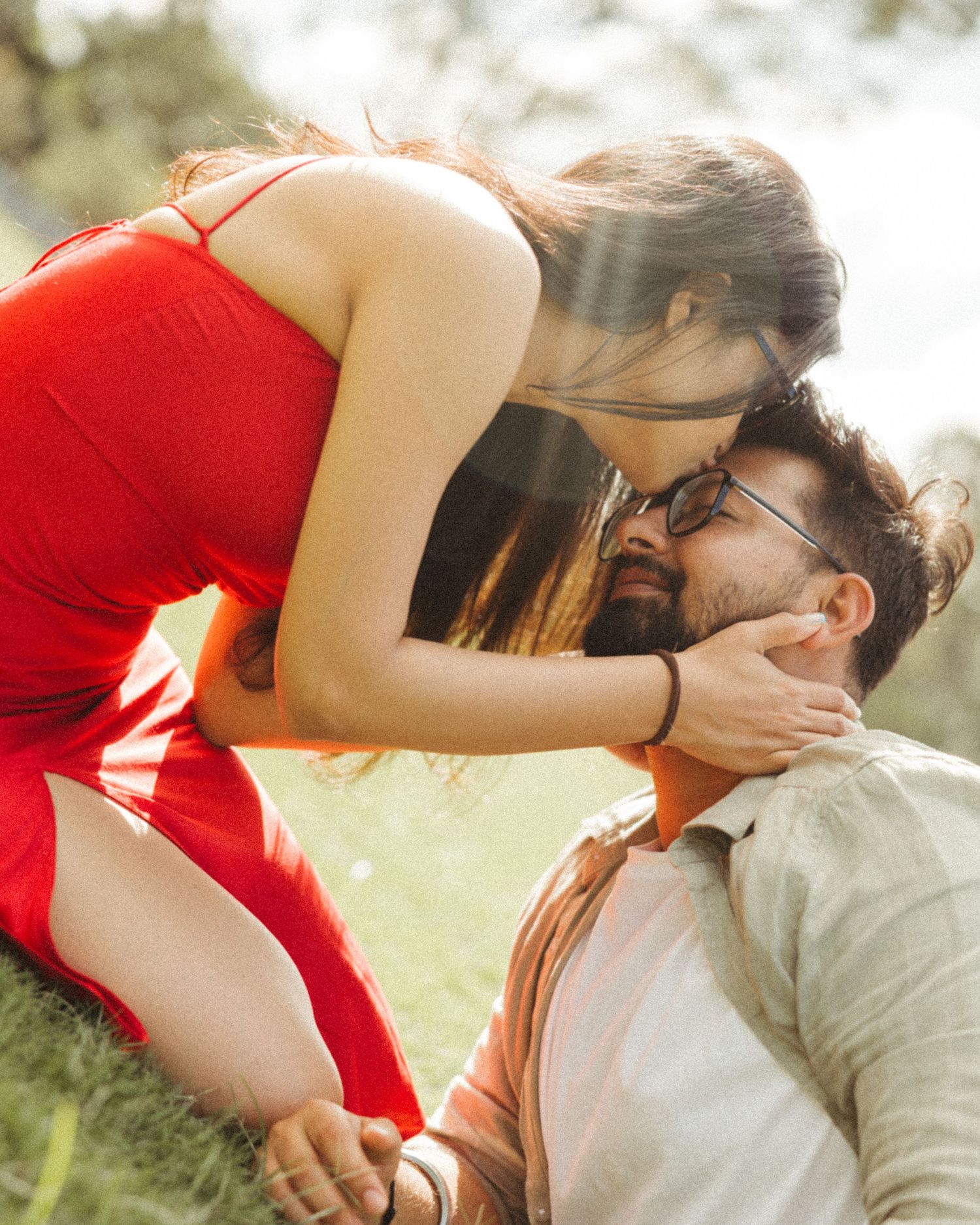 Romantic couple in red & white sharing tender sunlit outdoor moments, captured by the best wedding photographer in Mumbai near you