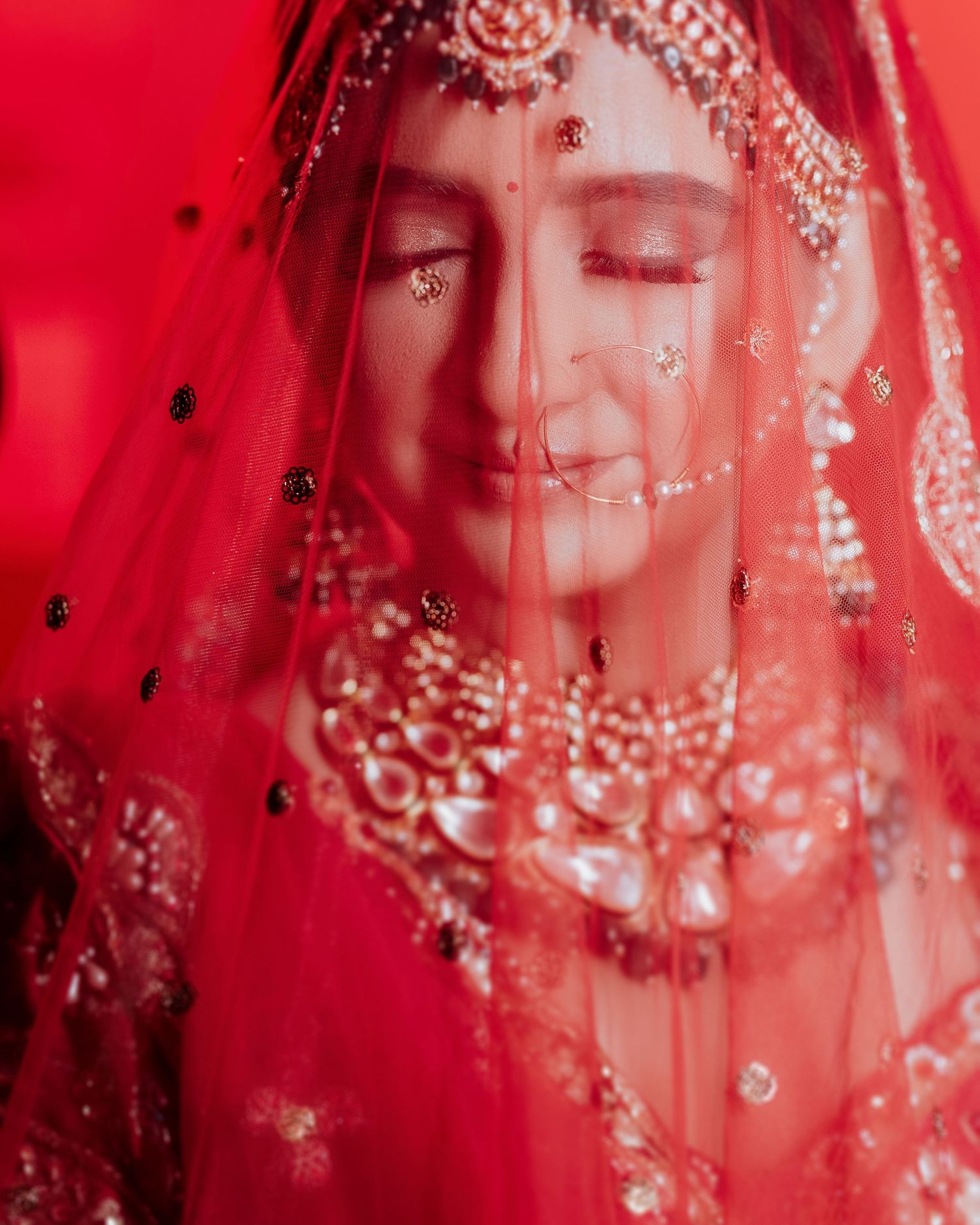 Stunning red bridal veil with intricate embellishment details, beautifully shot by a trusted wedding photographer near me in Mumbai.