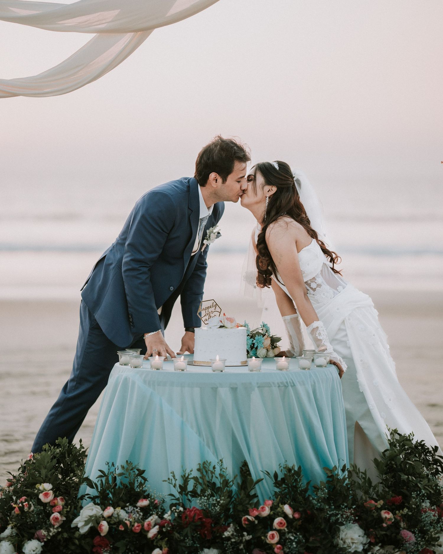 Romantic beachside wedding couple at a turquoise table during sunset, beautifully captured by a professional wedding photographer in Mumbai.