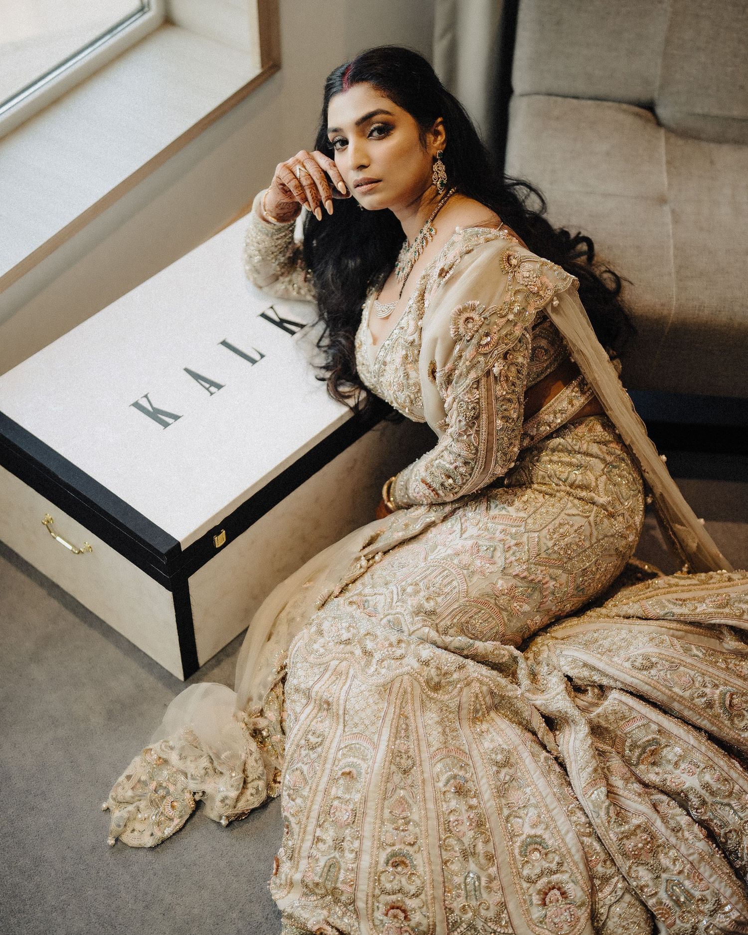 Looking for a wedding photographer in Mumbai? Elegant gold embroidered bridal dress in window light by Mumbai's finest wedding photographer.
