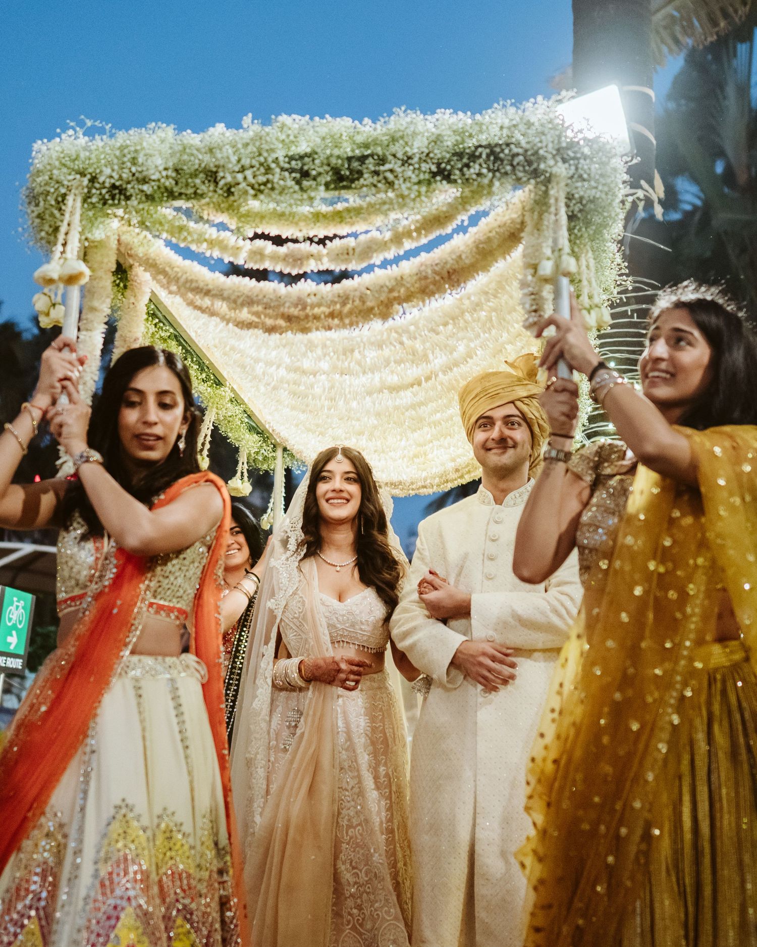 Traditional Indian wedding ceremony under a floral mandap with white & gold decor, beautifully captured by a wedding photographer in Mumbai