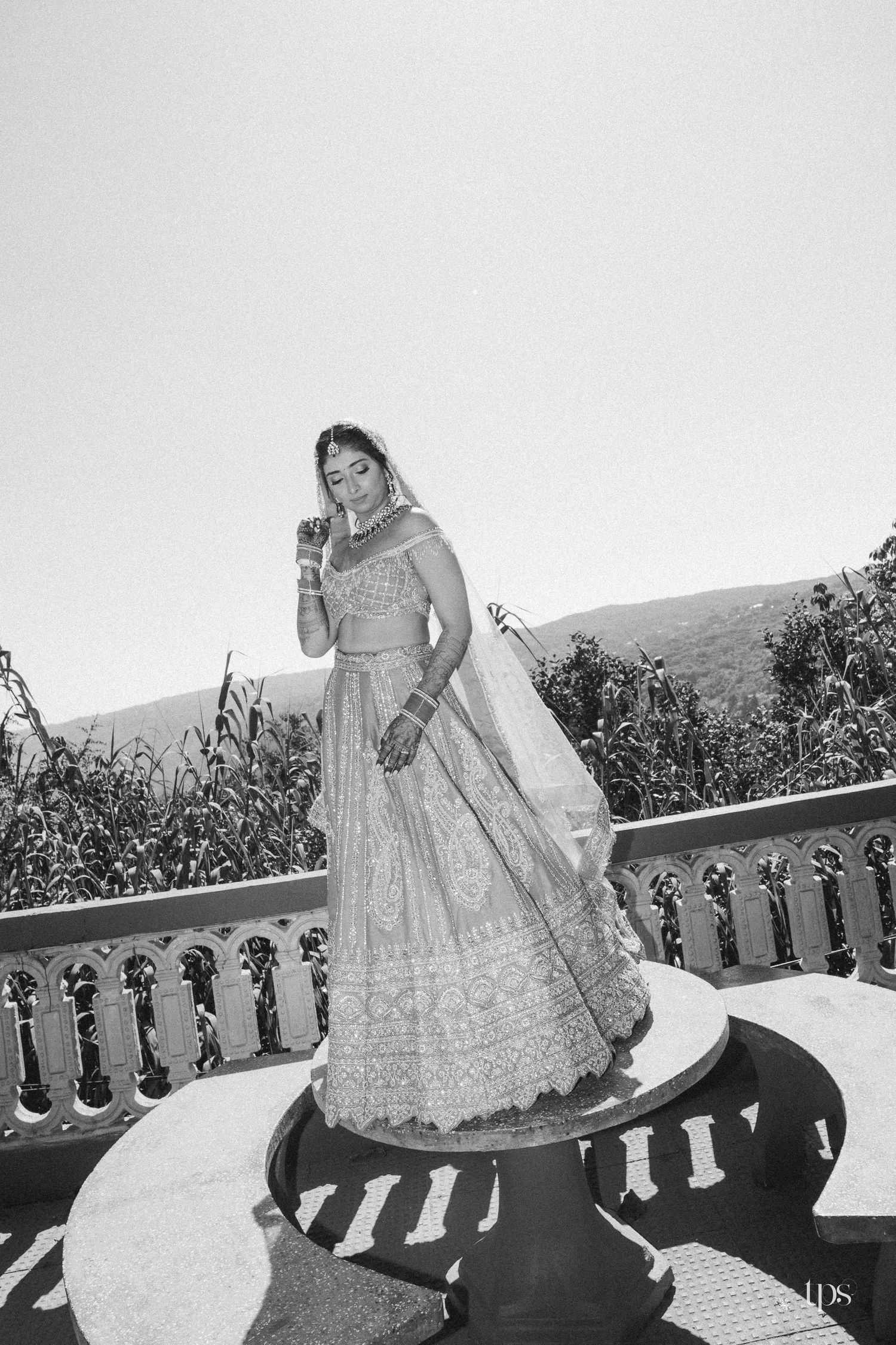 Black & white portrait of a bride in embroidered lehenga on a terrace balcony shot by a wedding photographer in Mumbai near me.