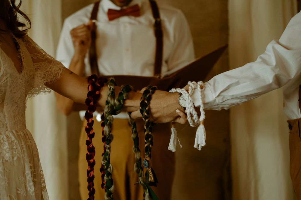 Close-up of handfasting ceremony with colorful ribbons binding couple hands together at altar.