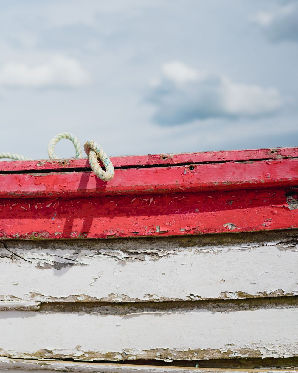 A close-up sequence showing the weathered edge of a red and white painted boat with peeling paint and rust.