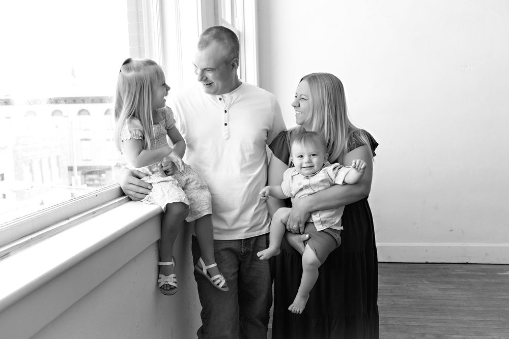 Family gather near a bright window for a candid moment, family photography Watertown WI
