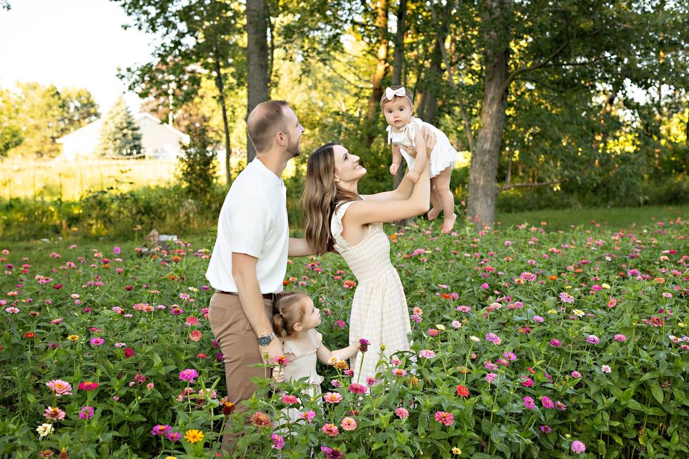 A couple dances and spins together in a field of pink wildflowers during golden hour sunset lighting. family photography Oconomowoc WI