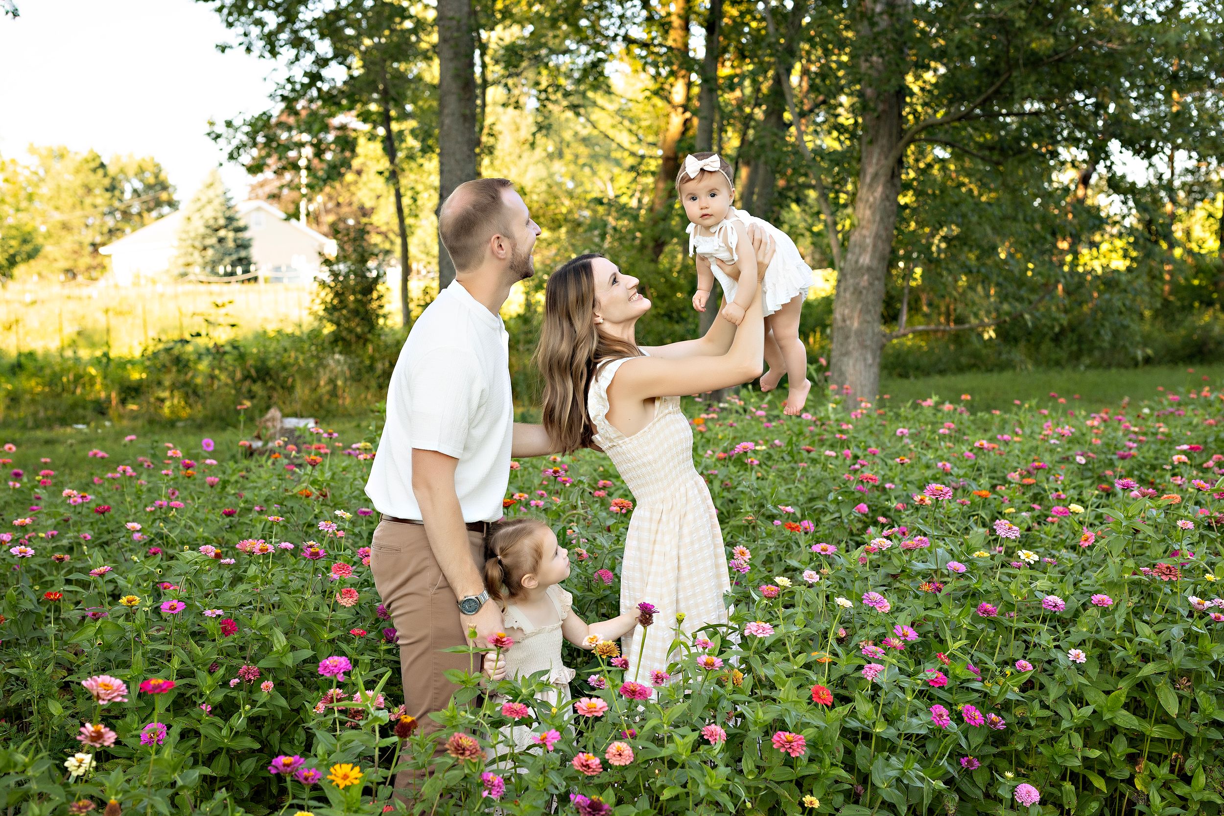 A couple dances and spins together in a field of pink wildflowers during golden hour sunset lighting. family photography Oconomowoc WI