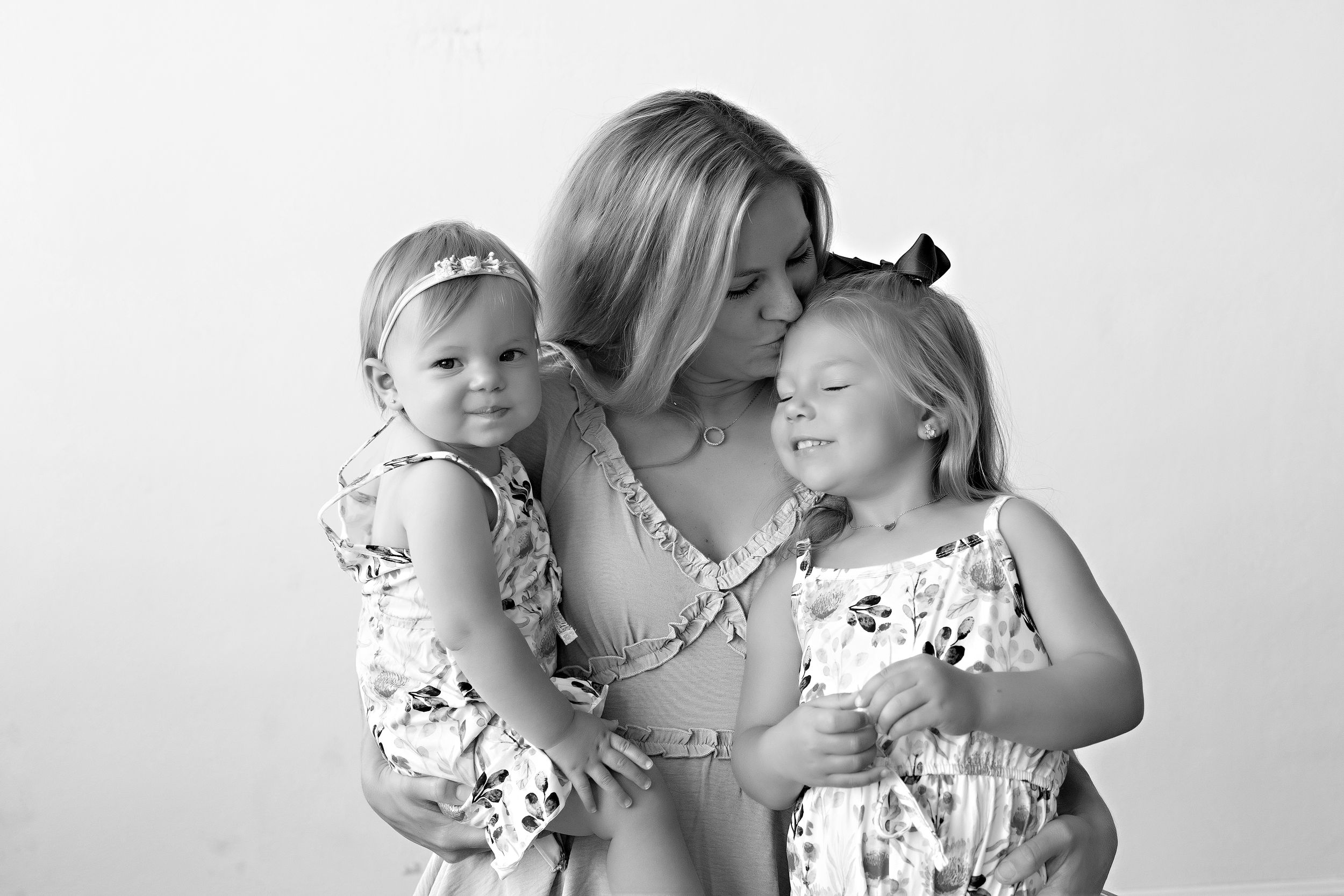 Black and white portrait showing tender family moment against white background. Mommy & me photo session with Kendall Kuss Photography in WI