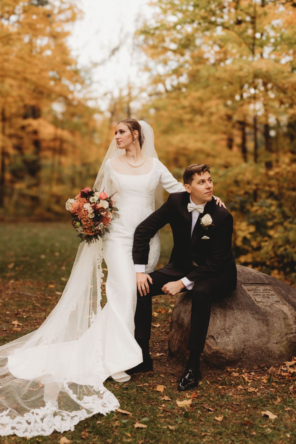 Wedding portraits on fallen leaves showing couple in elegant attire against autumn foliage.