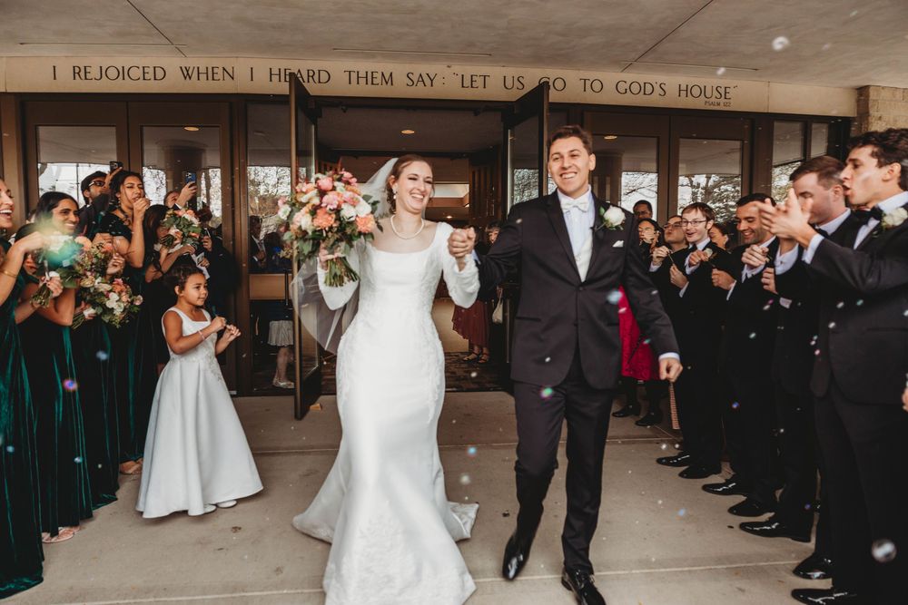 Wedding ceremony recessional in a modern church as guests line the aisle to celebrate the newlyweds.