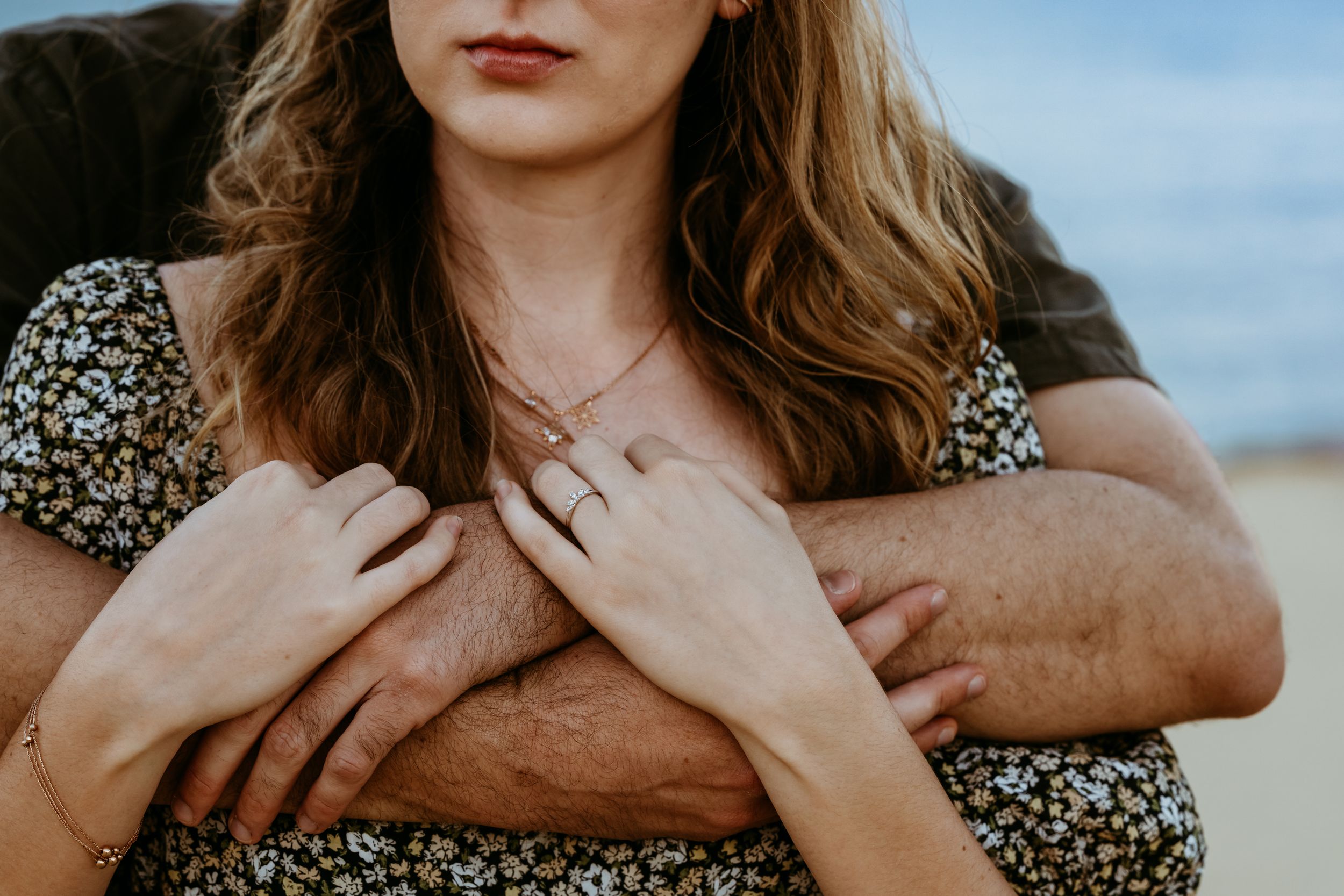 Close up of hands and floral dress fabric against a soft blurred background during golden hour.