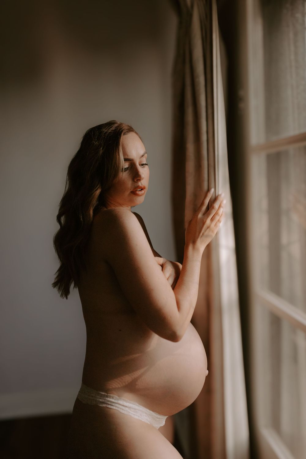 Silhouette portrait by window with soft natural lighting and sheer curtains.