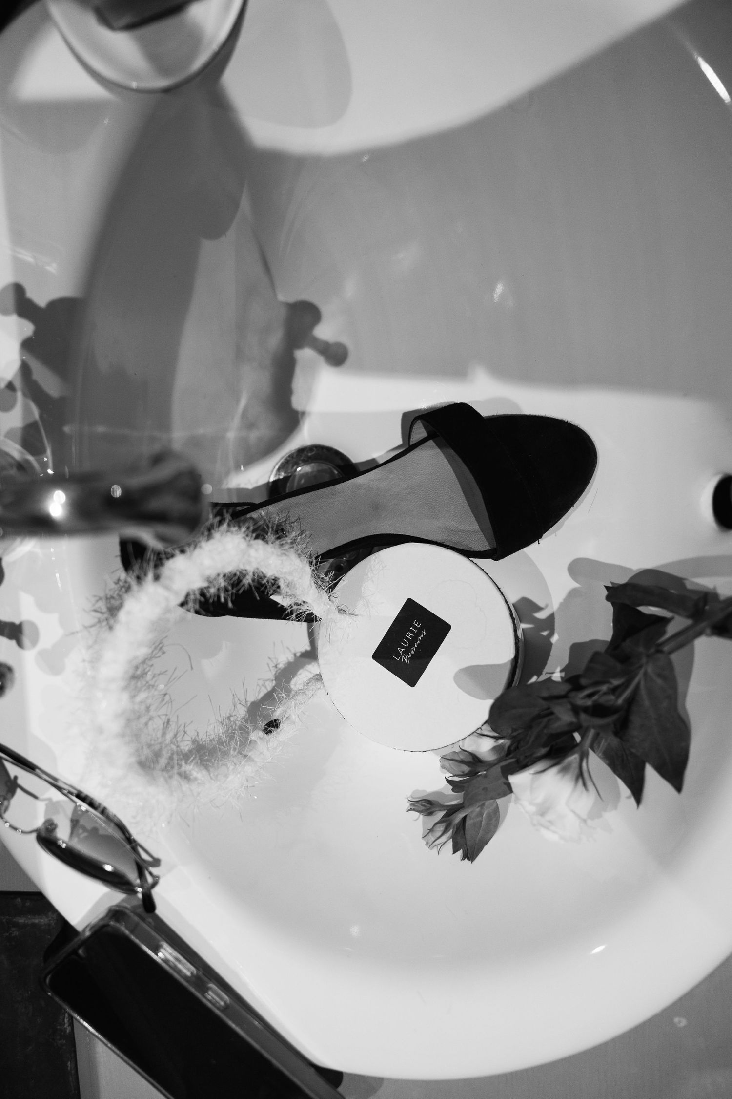 Black and white artistic still life photos of wedding details arranged on white surfaces.
