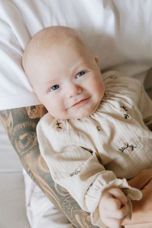 Baby in white clothing lying on blankets with small decorative bees scattered around.