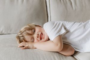 Close up of a child lying on a light colored couch with blonde hair.