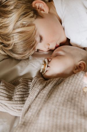 Intimate close-up of tender moment on light colored bedding.