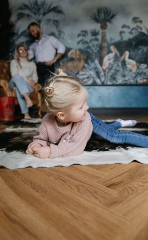 Lifestyle photo session against blue tropical wallpaper in warm lighting.