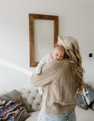 A tender moment with a baby being held against a wooden framed mirror backdrop.