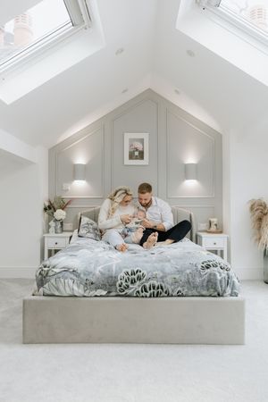 A cozy bedroom scene with white paneled walls, skylights, and modern decor.