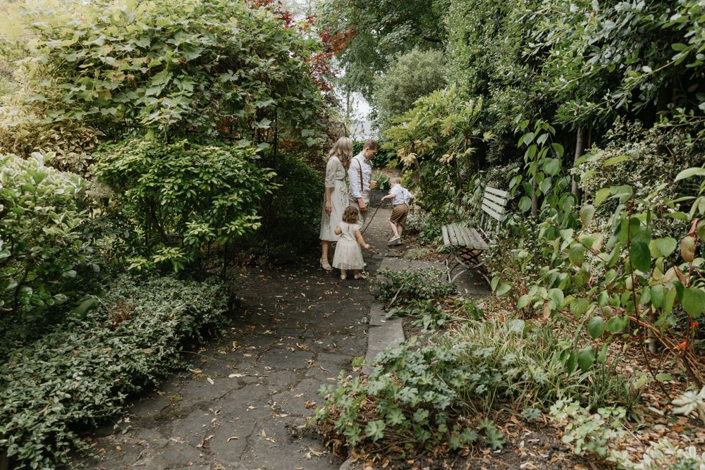 Lush green garden pathway winding through trees and foliage, creating a natural outdoor setting.