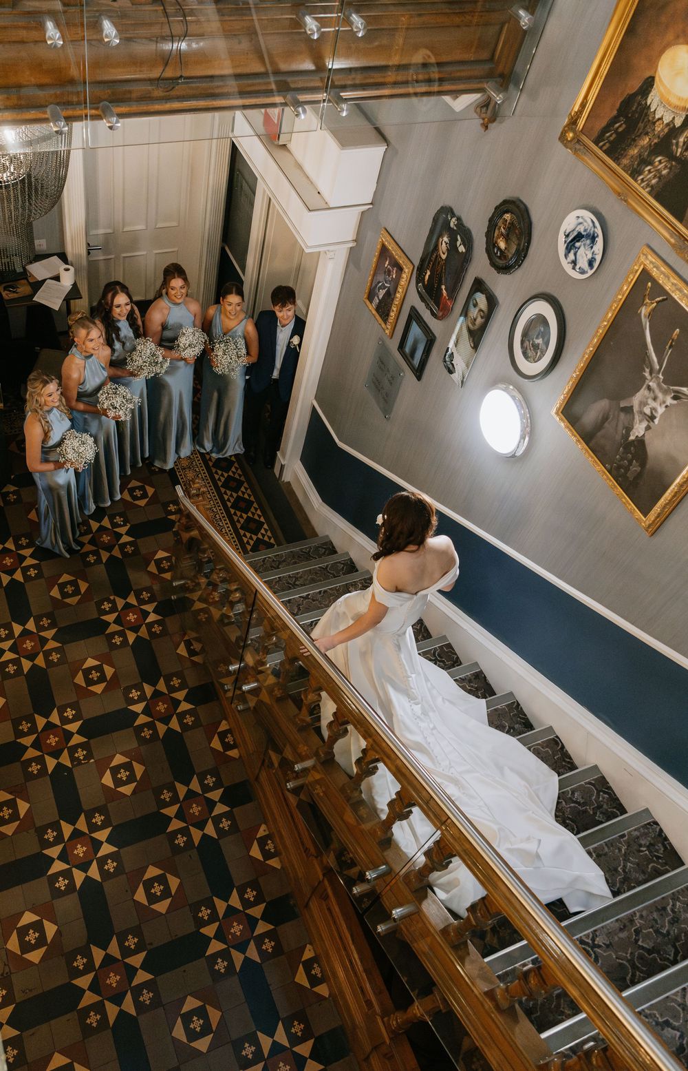 A grand staircase with decorative wooden flooring and vintage photographs on the walls.