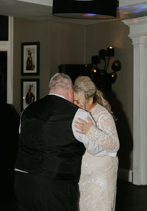Couple sharing an intimate slow dance together in a dimly lit reception hall.