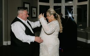 A couple in formal wedding attire dance together at their reception.