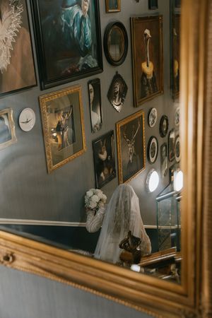 Vintage framed portraits and photographs hang on a wall in an antique gallery with golden curtains and soft lighting.
