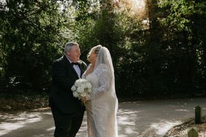 Newlywed couple shares romantic moments in a sun-dappled garden setting during their wedding photoshoot.