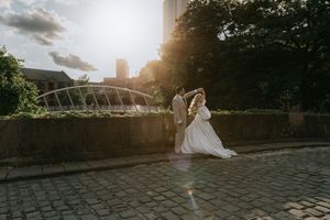 A sunset wedding moment captured on cobblestone streets with modern architecture and golden light.