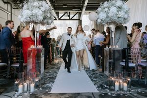 Wedding guests celebrate with sparklers outside at dusk, creating a magical tunnel of light for the couple.