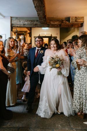 Wedding guests dance and celebrate together in a rustic indoor venue during a lively reception party.