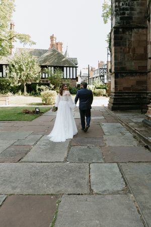 A series of five sequential photos showing a couple walking away through a stone archway in wedding attire.