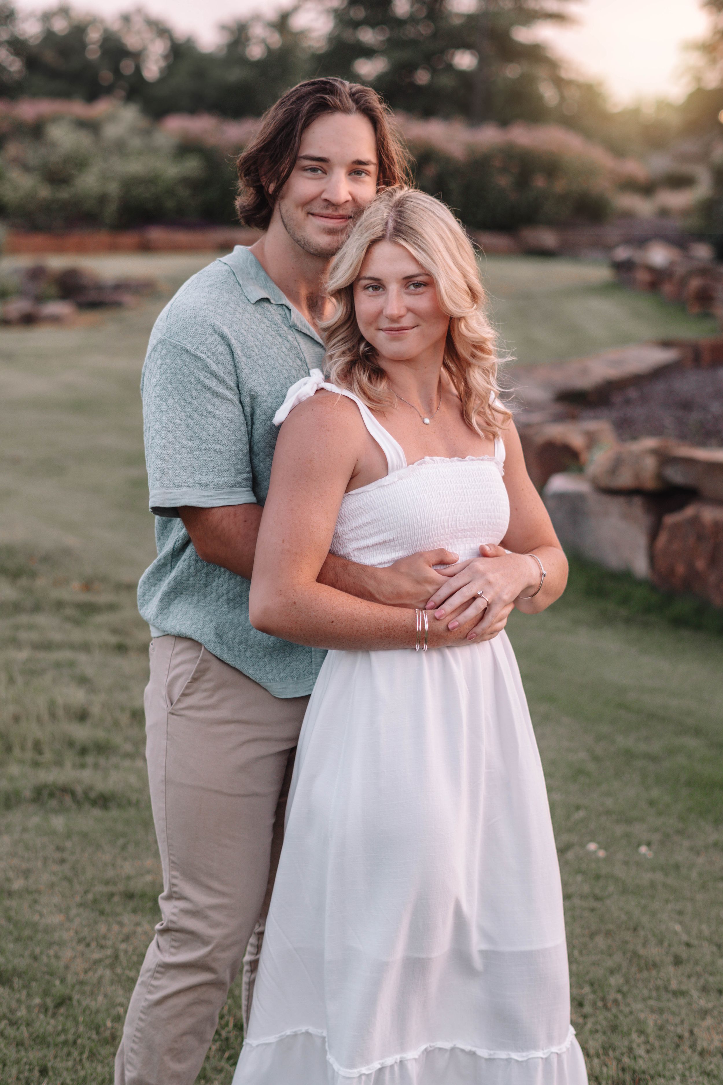 Romantic couple poses together outdoors at sunset wearing coordinating blue and white outfits.