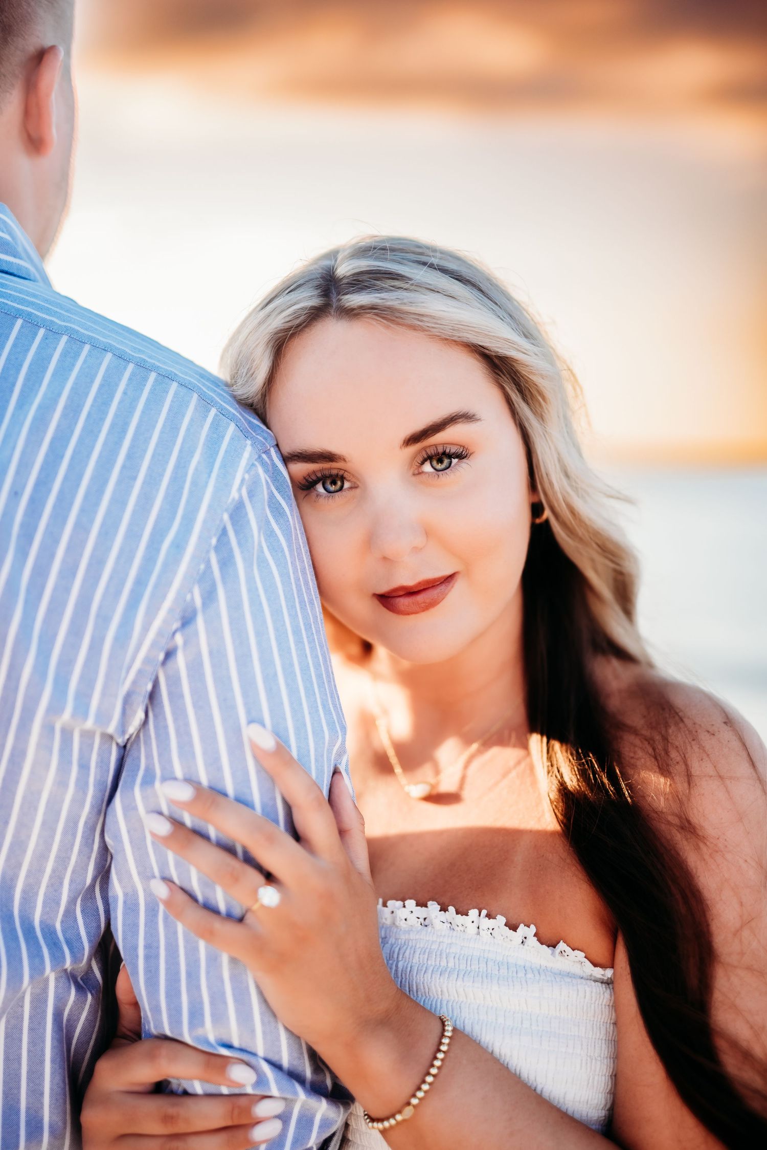 Romantic sunset photoshoot with couple in casual attire among trees.