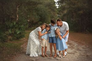 A family in blue shares a tender moment together on a forest path during an outdoor photo session by Marietta Photographer.