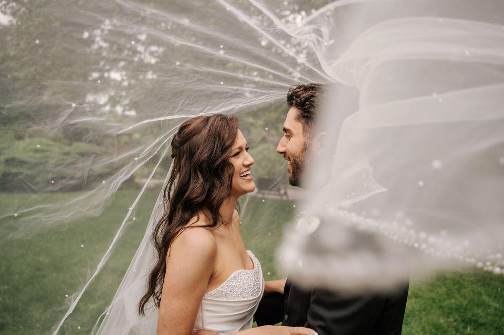 A romantic wedding couple shares an intimate moment as a veil flows in the wind on their special day.