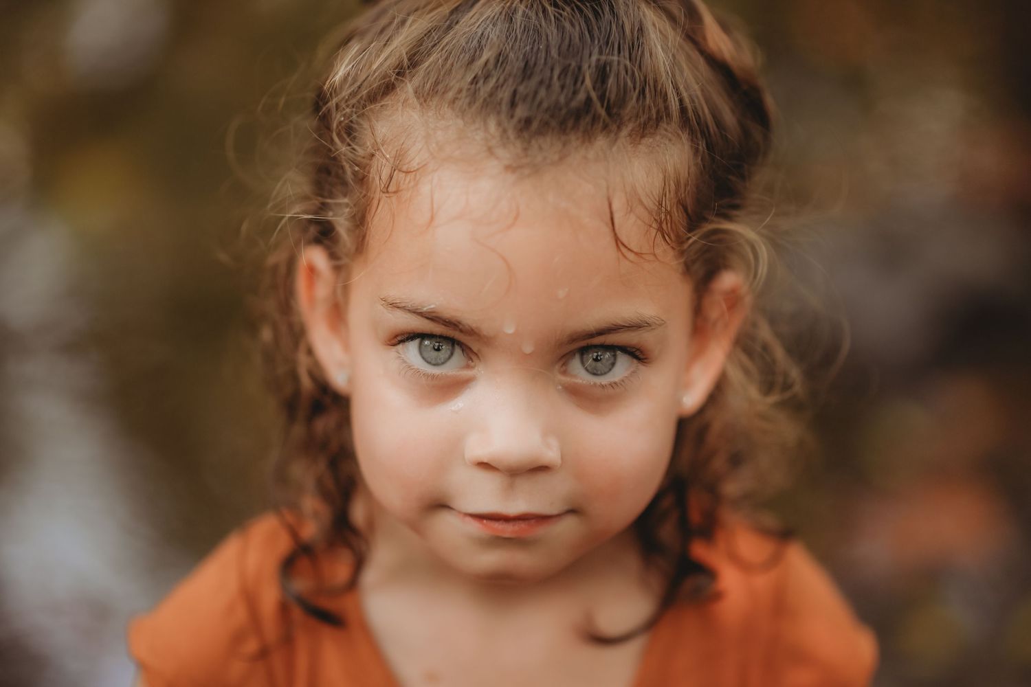 Close-up portrait with dramatic lighting highlights striking eyes and autumn tones.