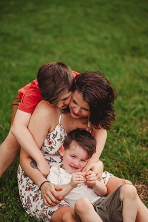 Candid family moment captured on grass showing affection and laughter.