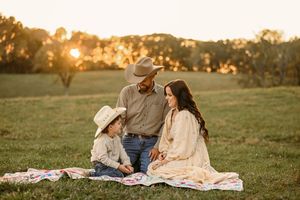 A picturesque country picnic scene at sunset with cowboy hats and a blanket on the grass.