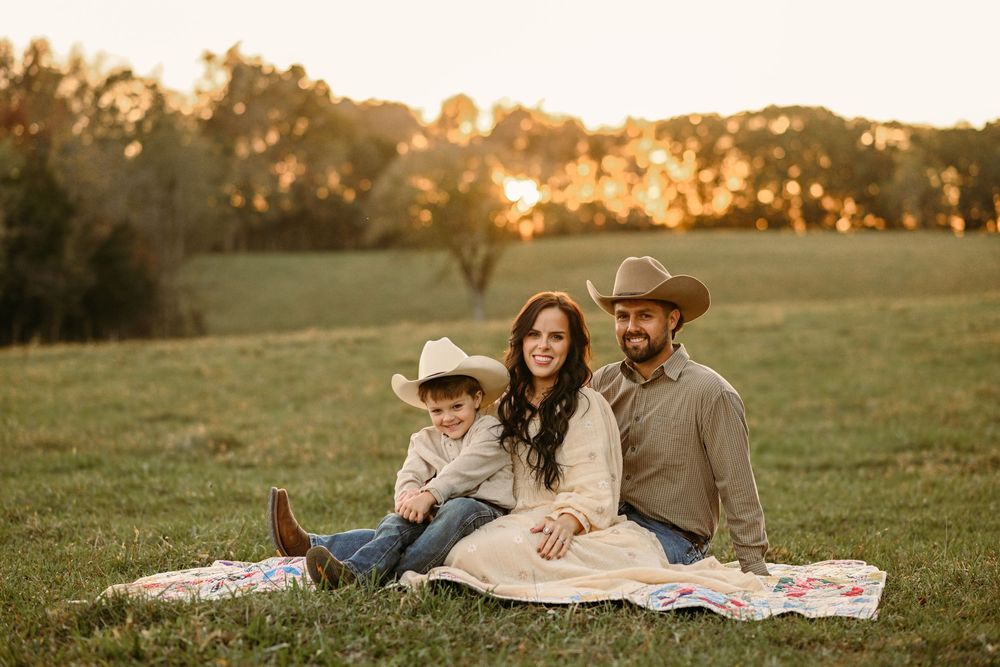 A relaxed outdoor family gathering on a blanket during golden hour.